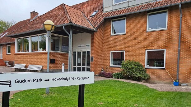 A brick building with a sign indicating 'Gudum Park' and 'Hovedindgang - Reception'. - 1 Person Holiday Park Home in Lemvig (Lemvig)