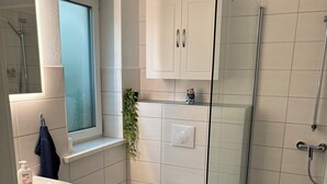 A modern bathroom with a toilet, sink, and shower area. - Cozy vacation apartment at Ammelshain Castle (Naunhof)