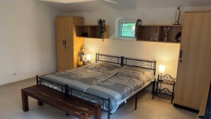 A bedroom with a bed, bedside tables, a bench, a wardrobe, and a window. - Cozy vacation apartment at Ammelshain Castle (Naunhof)