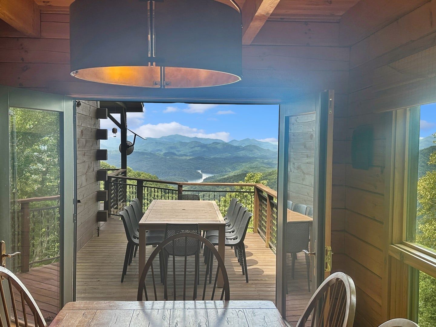 Varanda aberta com mesa e cadeiras, com vista para uma paisagem montanhosa.