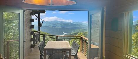 Eine offene Terrasse mit Tisch und Stühlen mit Blick auf eine gebirgige Landschaft.