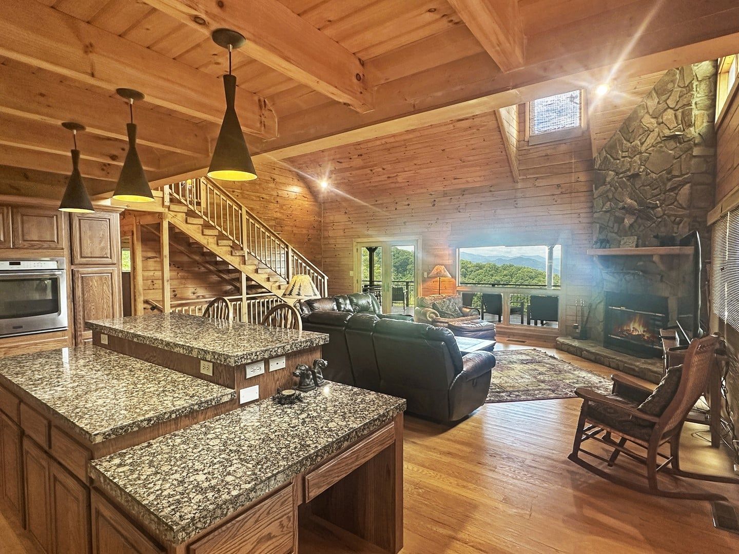 A spacious living area with a fireplace, a stone accent wall, and a view of the outdoors.