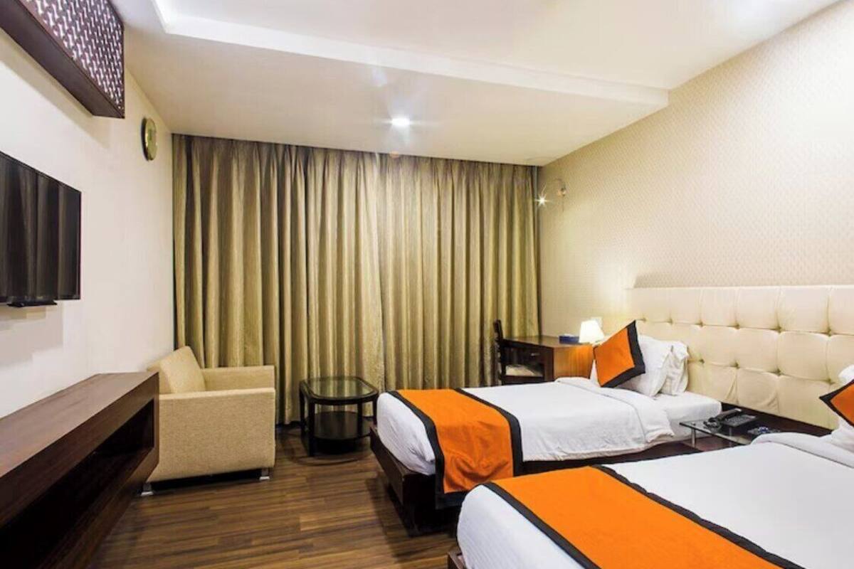 Habitación de hotel con dos camas, un sofá, un televisor y un escritorio.