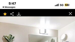 Une salle de bain moderne avec un meuble-lavabo foncé, des toilettes et des étagères en bois ornées d'objets décoratifs.