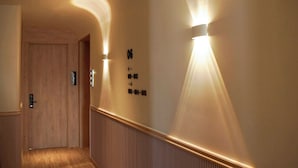 A hallway with wooden paneling, a door, and wall-mounted light fixtures. - Aizen Stay - District 1 (Ho Chi Minh City)