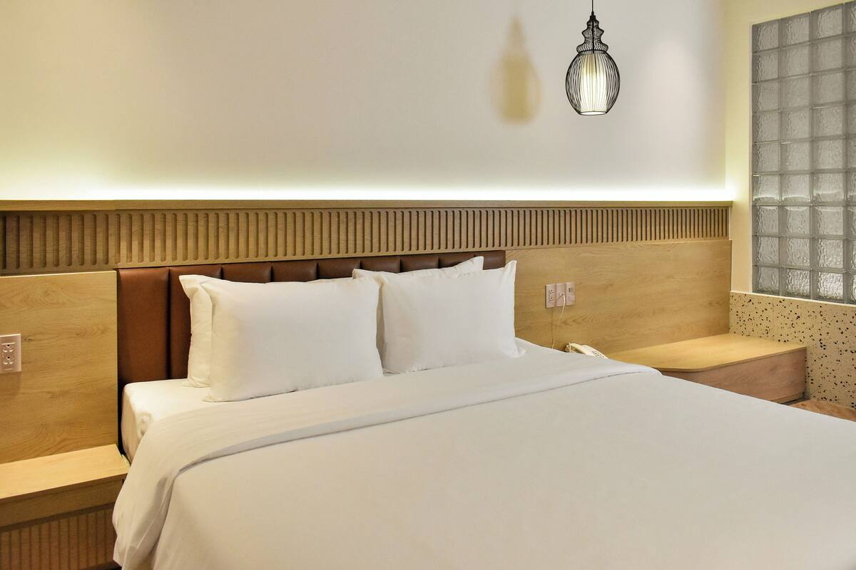 Ein Hotelzimmer mit einem großen Bett, einem Holz-Kopfteil, zwei Nachttischen und einer Wandleuchte.