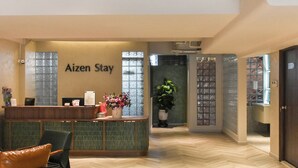A reception area with a reception desk, a chair, and a potted plant. - Aizen Stay - District 1 (Ho Chi Minh City)