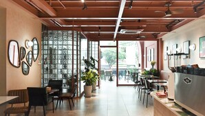 A modern cafe with a wooden ceiling, a patterned floor, and a seating area with tables and chairs. - Aizen Stay - District 1 (Ho Chi Minh City)