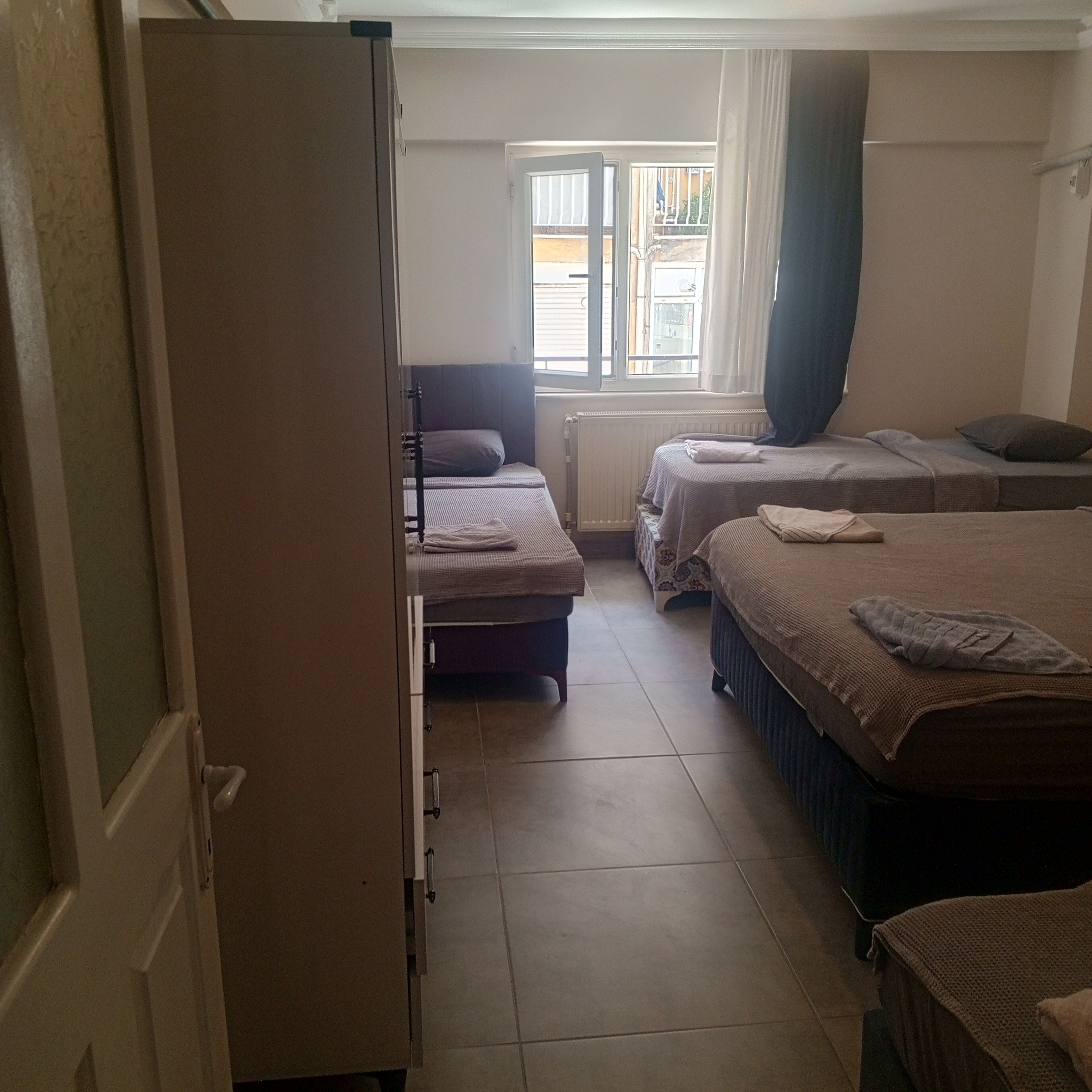 Une chambre avec deux lits, une armoire et une fenêtre avec des rideaux.