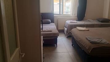 Une chambre avec deux lits, une armoire et une fenêtre avec des rideaux.