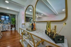 Un interior moderno con encimera de mármol, espejos con marco dorado y una bandeja decorativa.