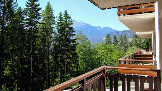 A wooden balcony with a view of a forest and mountains. - Ca' Del Molin, spacious apartment with view (Cortina d'Ampezzo)
