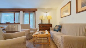 A cozy living room with two armchairs, a sofa, a wooden coffee table, and a dresser with lamps. - Ca' Del Molin, spacious apartment with view (Cortina d'Ampezzo)