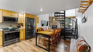 Una cocina moderna con armarios de madera, electrodomésticos de acero inoxidable y una zona de comedor con mesa y sillas de madera.