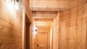 A wooden interior hallway with a light fixture and a door at the end. - Large Duplex for 10 People At the Base of the Slopes & Bike Park • Garage & View (Châtel)
