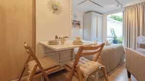 Una habitación compacta con zona de comedor, cama y ventana con cortinas.