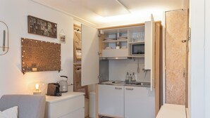 Cocina compacta con muebles blancos, cafetera y microondas.