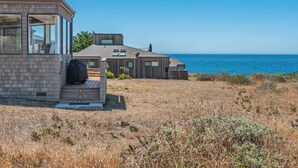 Una casa sul lungomare con un'ampia finestra, un terrazzo e vista sull'oceano.