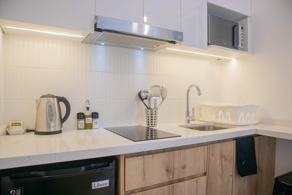 A modern kitchen with white tiles, stainless steel appliances, and wooden cabinets.