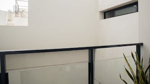 Een modern gebouw met een balkon, grote ramen en een plant.