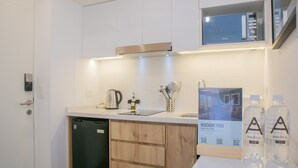 Een moderne keuken met witte kasten, een ingebouwde magnetron en een vaatwasser. Er staan twee flessen water op het aanrecht.