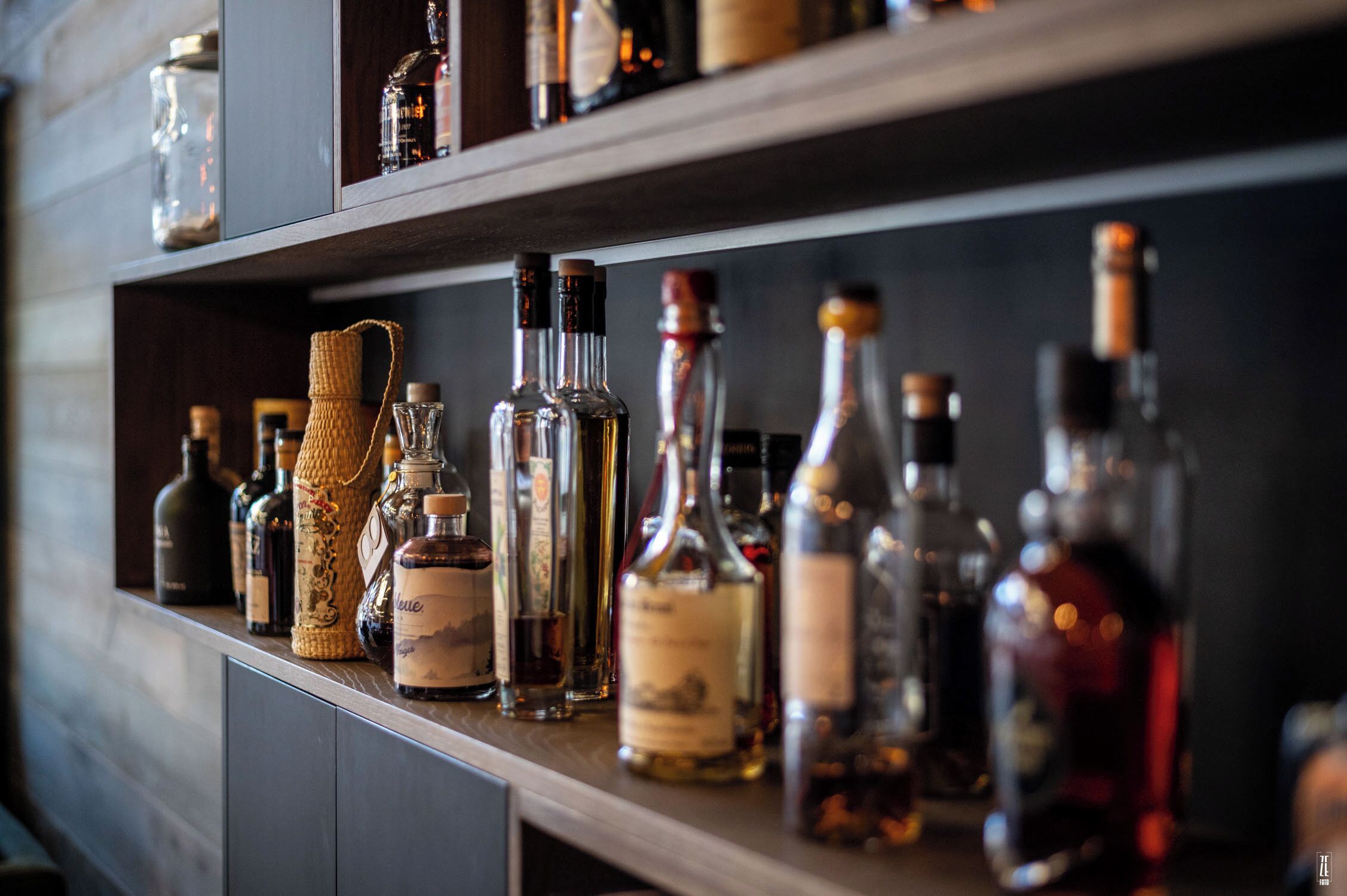 Een bargedeelte met planken waarop verschillende flesjes drank staan.