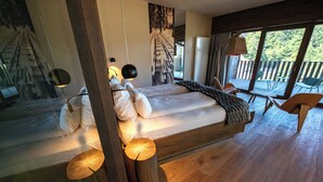 A bedroom with a wooden bed, a large window, and a view of the outdoors. - Chalet Hôtel le Collet & Spa (Xonrupt-Longemer)
