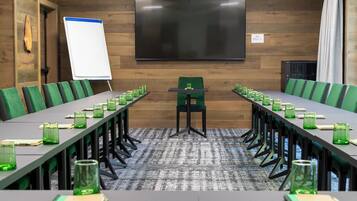 A conference room with a long table, green chairs, and a whiteboard.