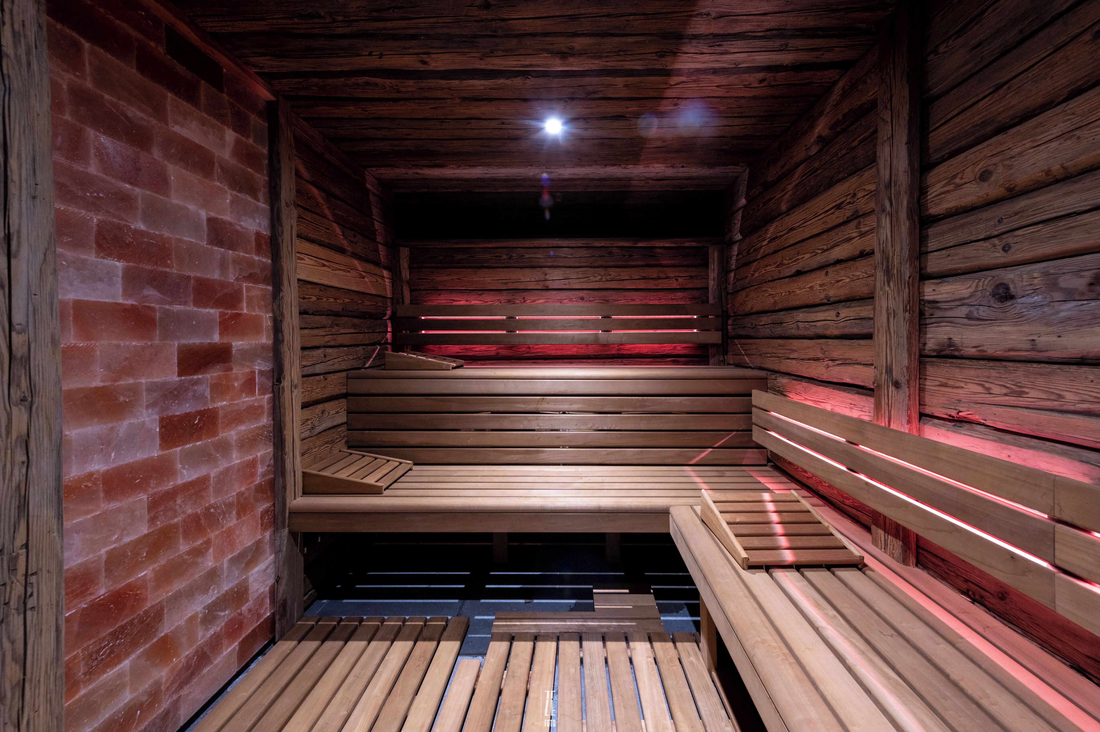 A sauna with wooden benches and a brick wall.