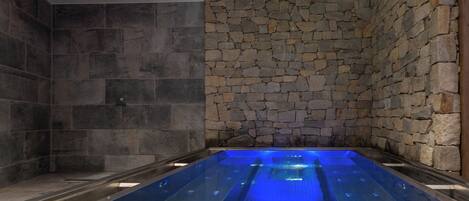 A spa area with a stone wall and a glass hot tub.