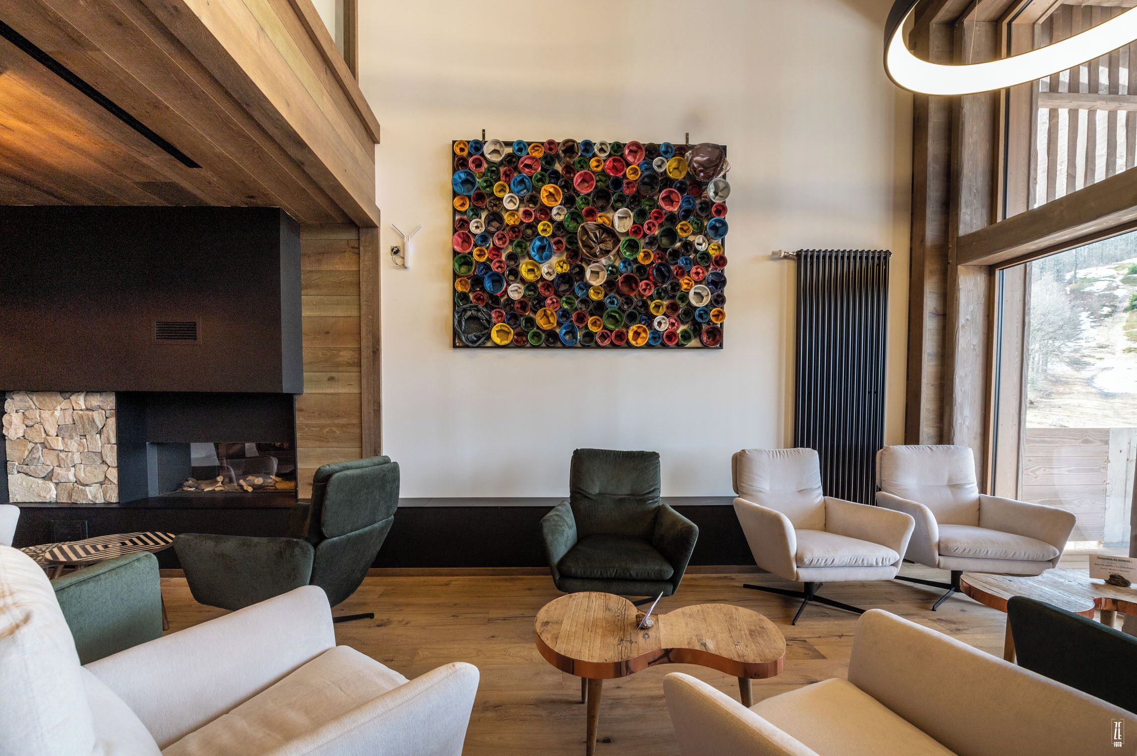 A modern living room with a fireplace, comfortable seating, and a colorful abstract art piece on the wall.