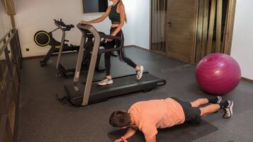 Een sportschool met loopbanden, een hometrainer en een grote fitnessbal.