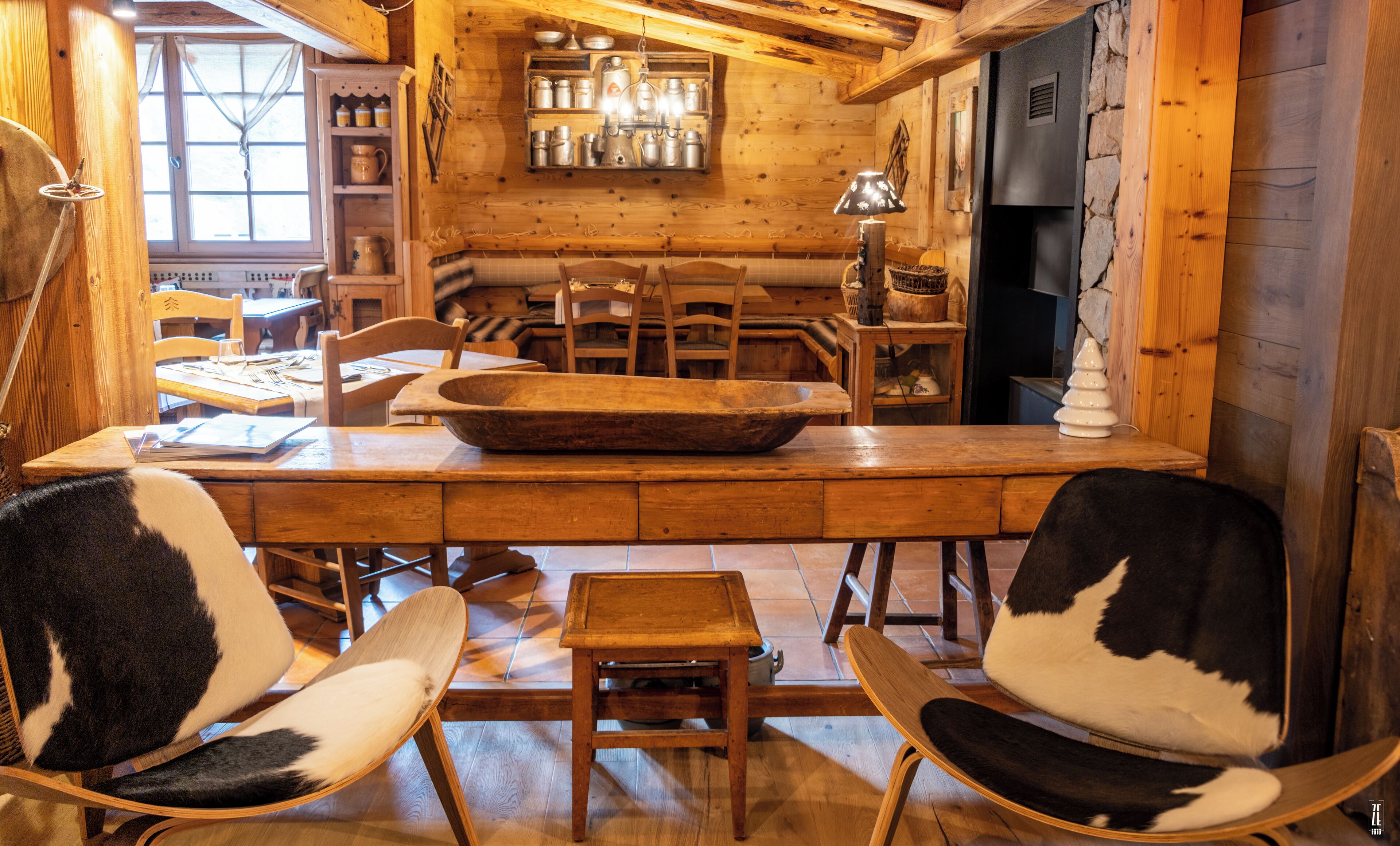 Un interior de madera con una larga mesa de comedor, sillas y una chimenea.