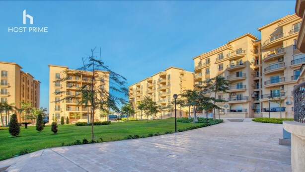 A residential complex with multiple apartment buildings, a central paved area, and some greenery.