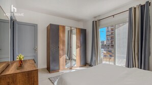 A modern hotel room with a large bed, a wardrobe, and a balcony with a view of the city.