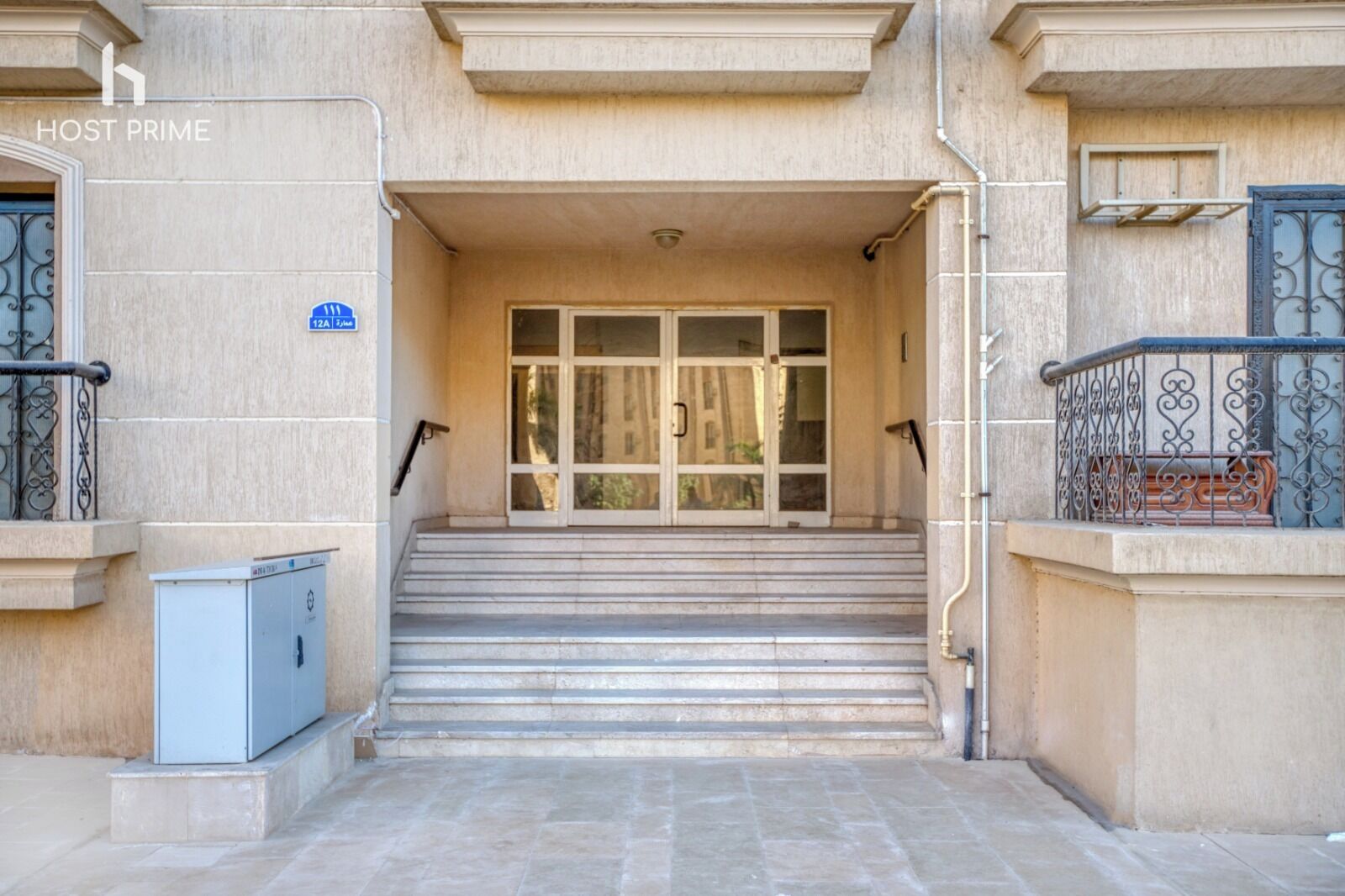 A building entrance with a set of stone steps leading up to a glass door.
