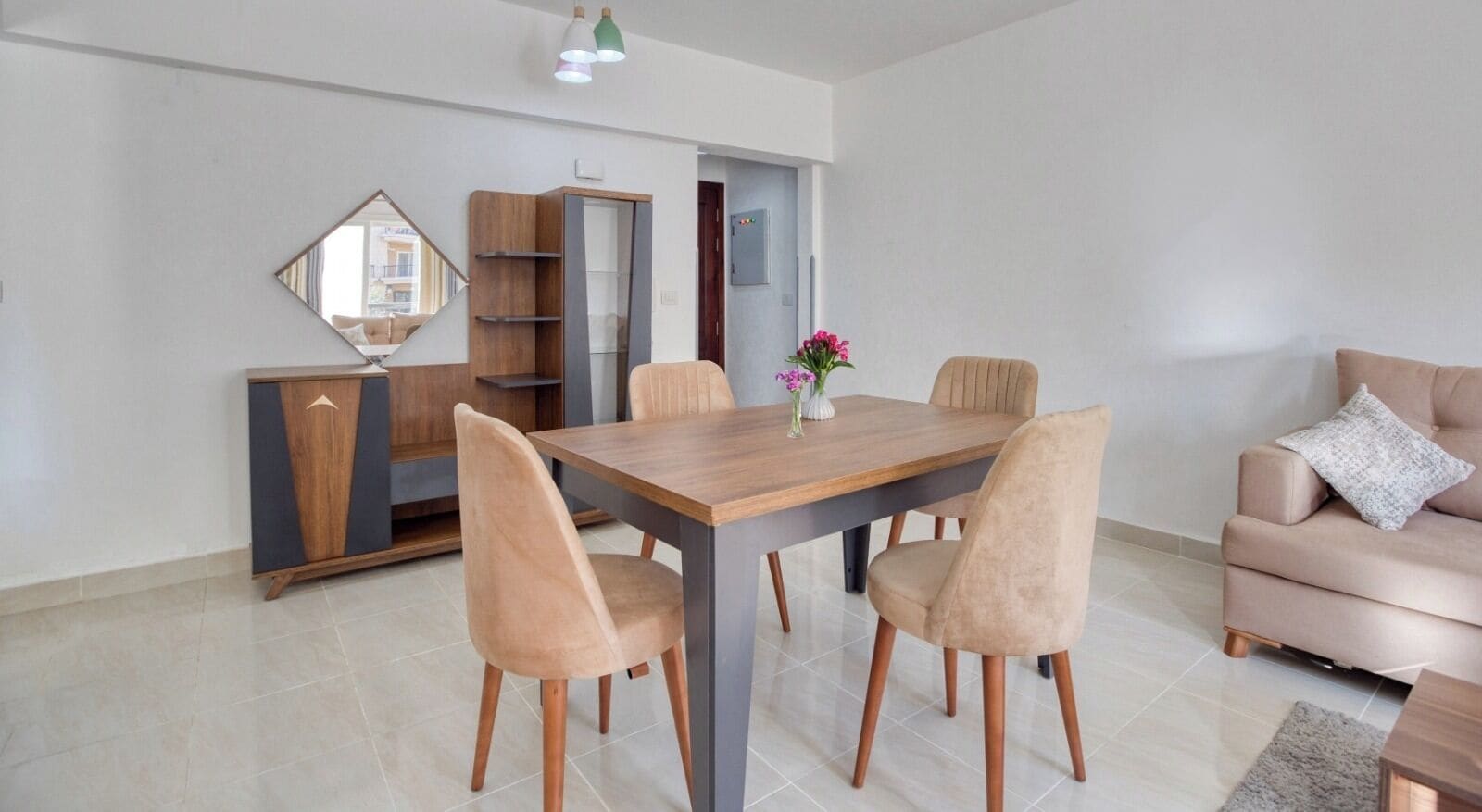 Een moderne eethoek met een houten tafel, vier stoelen, een bank en een spiegel aan de muur.
