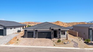 A modern residential area with houses featuring dark roofs, stone accents, and a desert landscape in the background. - Four Paws & Fairways | Golf Course Front | Pet Friendly | Over $500 in complimentary activities (Mesquite)