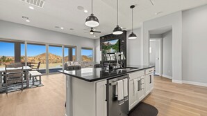 A modern kitchen with a large island, stainless steel appliances, and pendant lighting. - Four Paws & Fairways | Golf Course Front | Pet Friendly | Over $500 in complimentary activities (Mesquite)