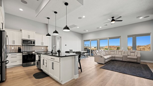 A modern kitchen with white cabinets, a central island, and a dining area with a beige sofa. - Four Paws & Fairways | Golf Course Front | Pet Friendly | Over $500 in complimentary activities (Mesquite)