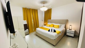 Un dormitorio con cama, mesitas de noche, un espejo y una lámpara en el techo.