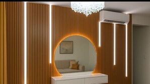 Una habitación moderna con un espejo grande, un tocador blanco y paneles de madera verticales.