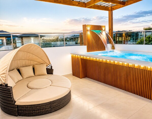 A rooftop terrace with a hot tub, a circular seating area, and a wooden pergola.