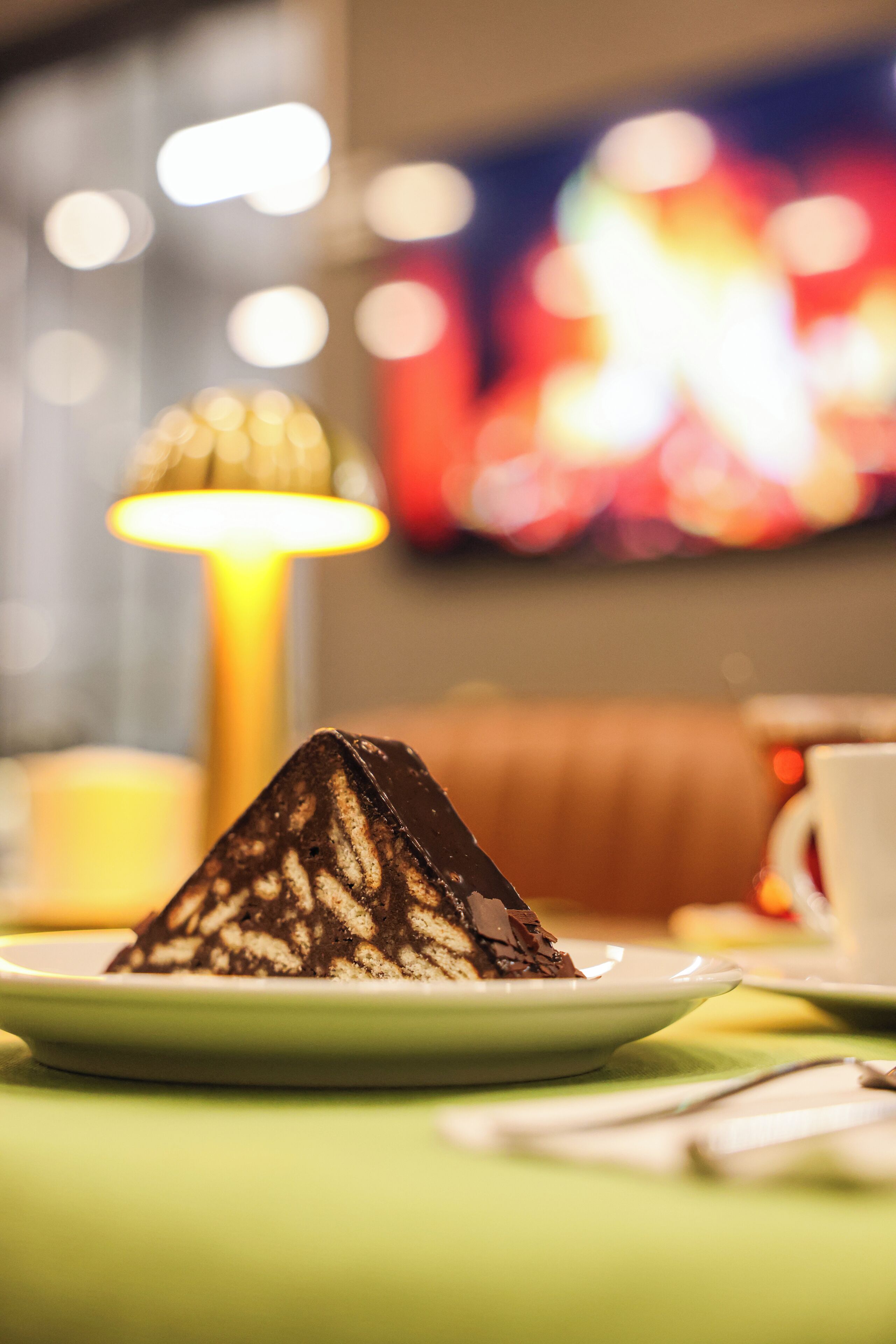 Un postre sobre un plato, con un fondo desenfocado de una mesa, una lámpara y un sofá.