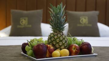 A fruit platter on a table with a bed and pillows in the background.