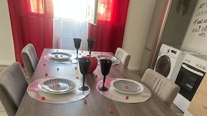 A dining table set with plates, glasses, and red decorative items.