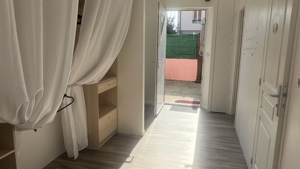 A hallway with wooden flooring, white walls, and a door leading to a balcony.