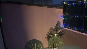 An outdoor patio area with a table and chairs, a decorative lamp, and string lights.