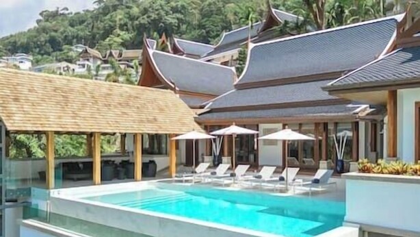 A modern pool area with lounge chairs and umbrellas, surrounded by traditional architecture. - Zenith Villa | Luxury - 6 Bedroom Villa in Surin with Sea View (Cheong Thale)