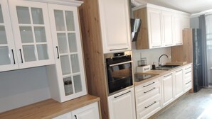 Une cuisine moderne avec des meubles blancs, un plan de travail en bois et des appareils électroménagers en acier inoxydable.